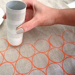 Hand holding a toilet paper tube as a print method on fabric